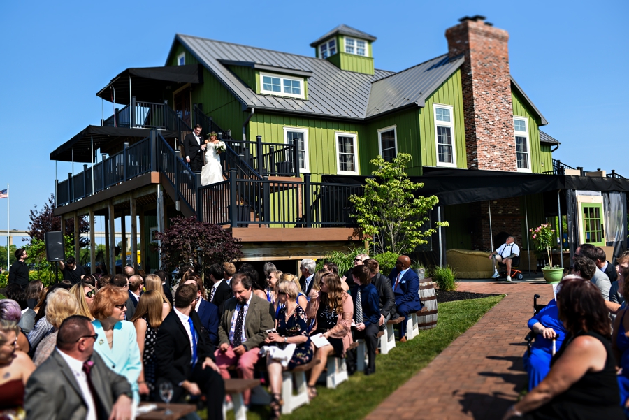 A bride walks down the staircase to her waiting father during her wedding ceremony at Thousand Acre Farm.